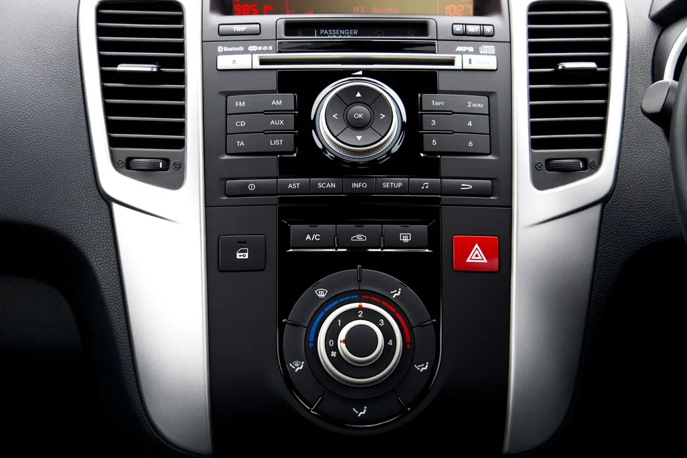 Console centrale d'une voiture avec la façade à boutons d'un autoradio sans écran et les molettes de ventilation