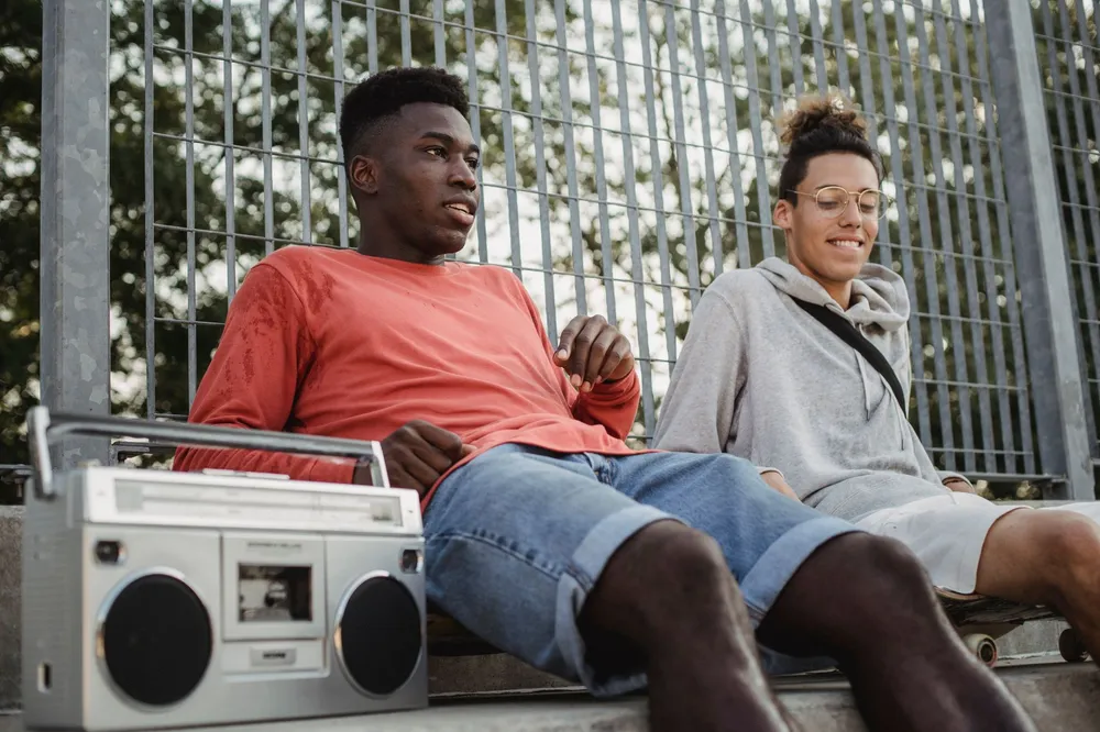 Groupe d'amis écoutant de la musique avec une enceinte portable en extérieur l'été